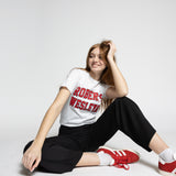 Person wearing a white Roberts Wesleyan t-shirt with red text, black pants, and red sneakers on a white background