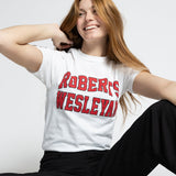 Person wearing a white Roberts Wesleyan t-shirt with red text, black pants, and red sneakers on a white background
