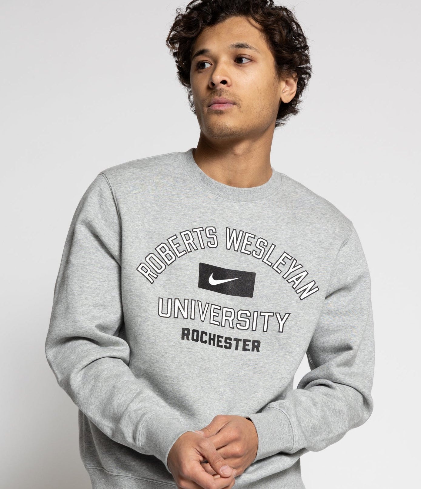 Person wearing a gray sweatshirt with 'Roberts Wesleyan University Rochester' text and Nike logo.