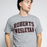 Person wearing a gray t-shirt with 'Roberts Wesleyan' printed on it against a white background