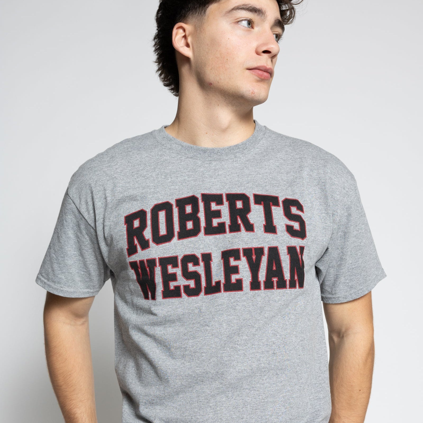 Person wearing a gray t-shirt with 'Roberts Wesleyan' printed on it against a white background