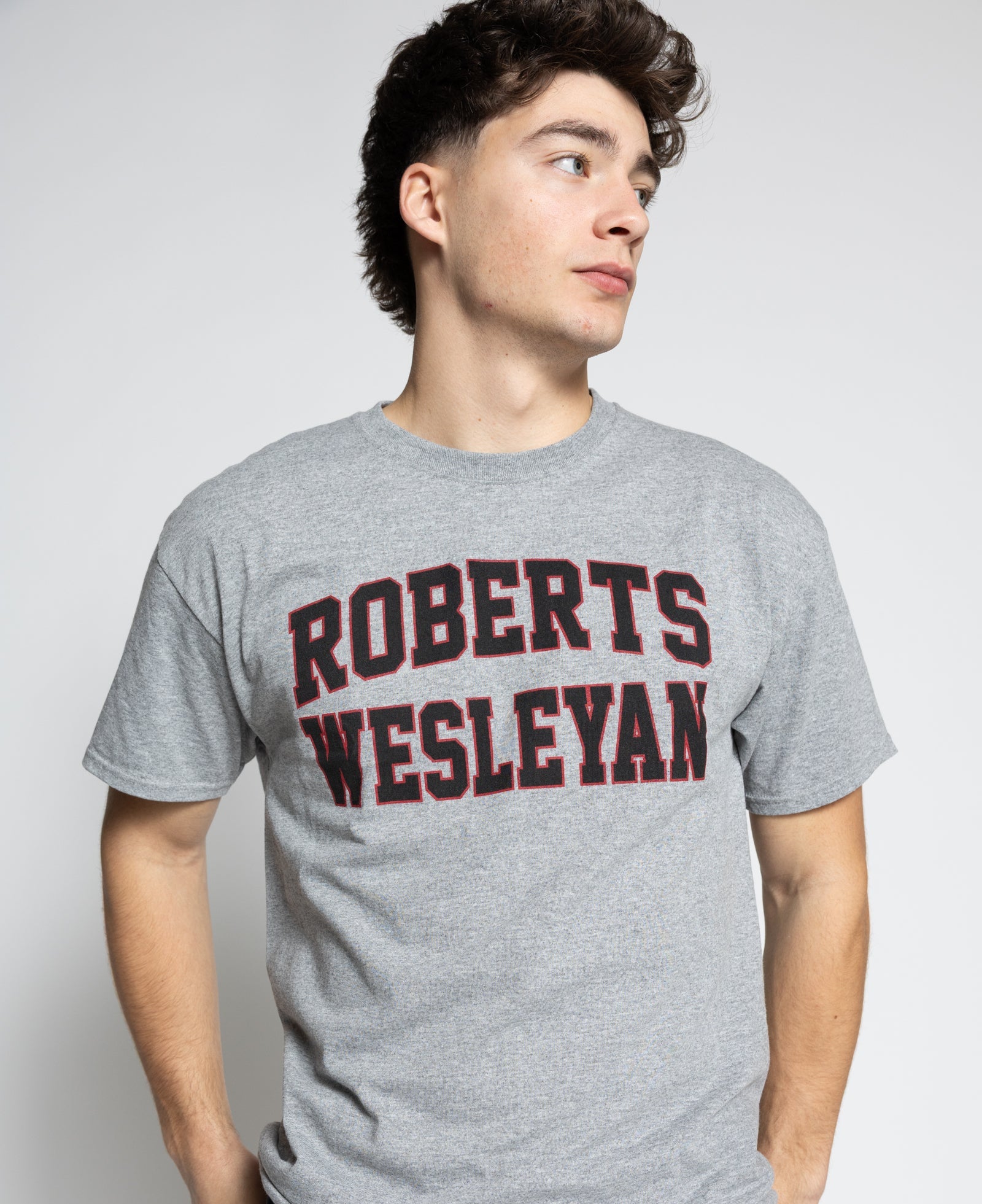 Person wearing a gray t-shirt with 'Roberts Wesleyan' printed on it against a white background